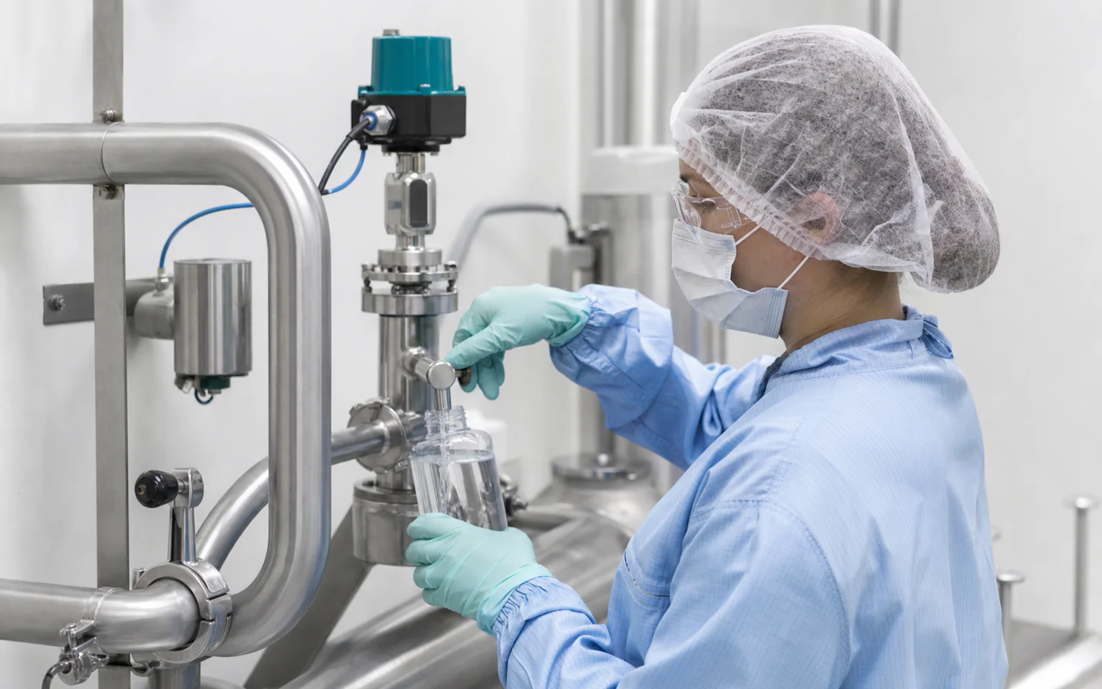 Cleanroom technician sampling purified water from a sanitary system